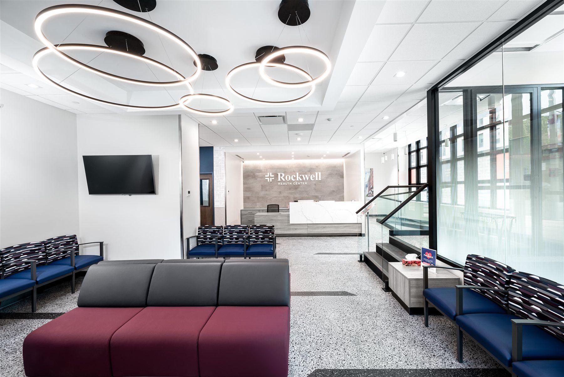 The Rockwell waiting room in Astoria, with ring pendant lighting above navy and burgundy seating